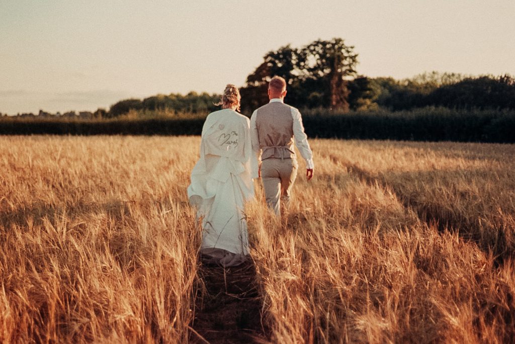 Bride and groom in a field during golden hour, captured on 35mm film. South Wales
