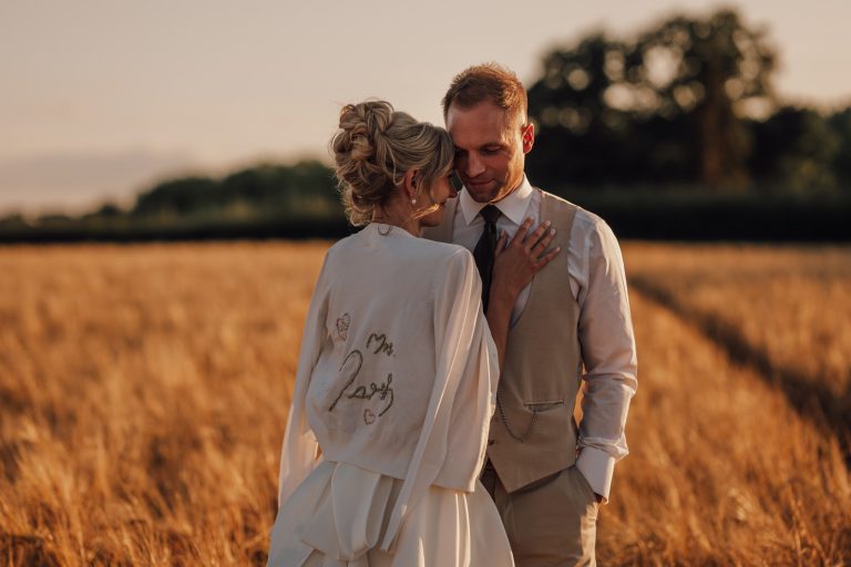 Welsh countryside wedding, bride and groom embrace in wheat field in golden sun light