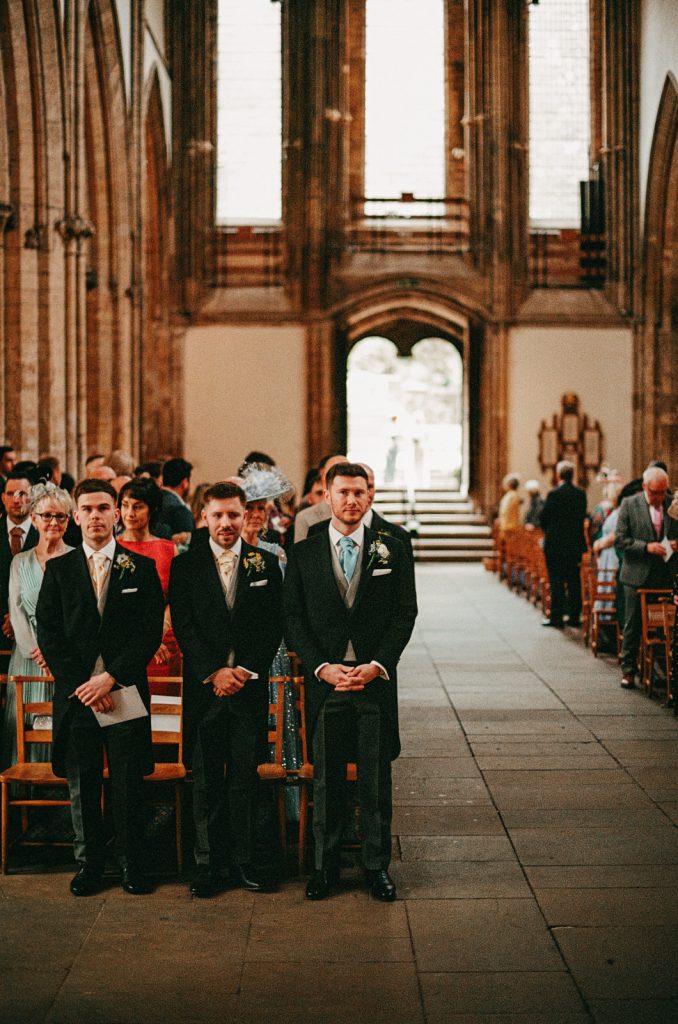 35mm analogue film photograph of groom waiting for bride Llandaff Cathedral in Cardiff, South Wales