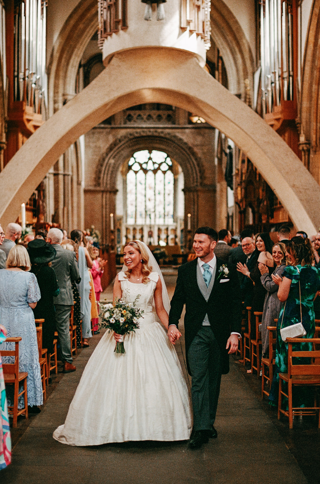 35mm analogue film photograph of bride and groom walking down the aisle of Llandaff Cathedral in Cardiff, South Wales.