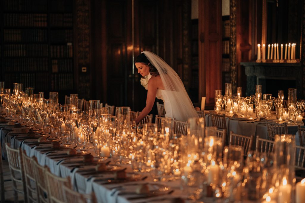 Bride inspects the candle light at her Winter wedding in Clevedon Hall