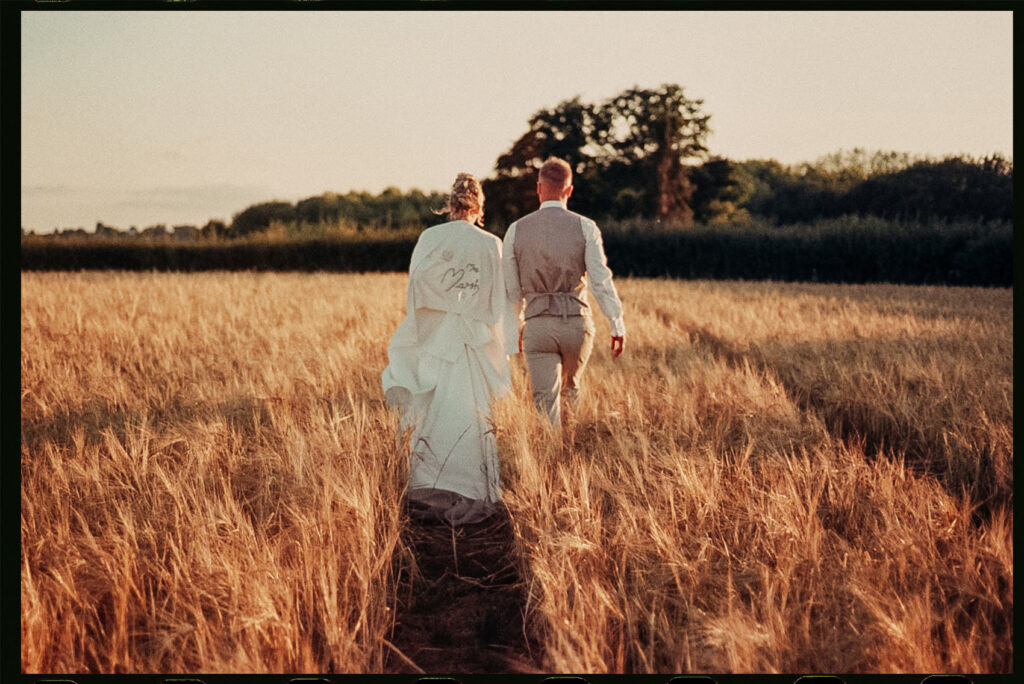 Film wedding photography, bride and groom in a field during golden hour, captured on 35mm film. South Wales